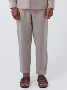 Person wearing beige pants and brown sandals on a white background