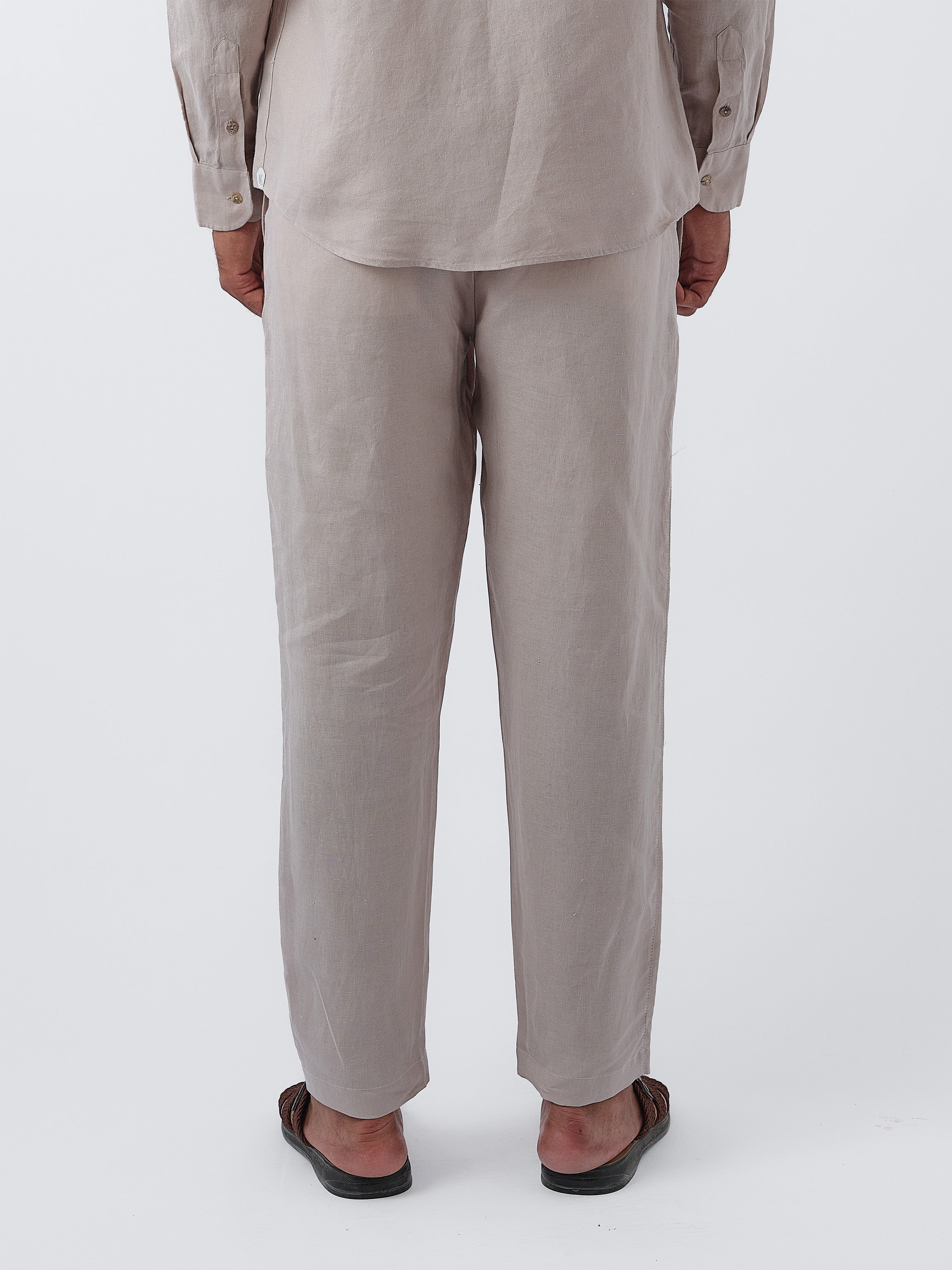 Person wearing a beige linen pants on a white background