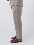 Person wearing beige pants and brown sandals on a white background