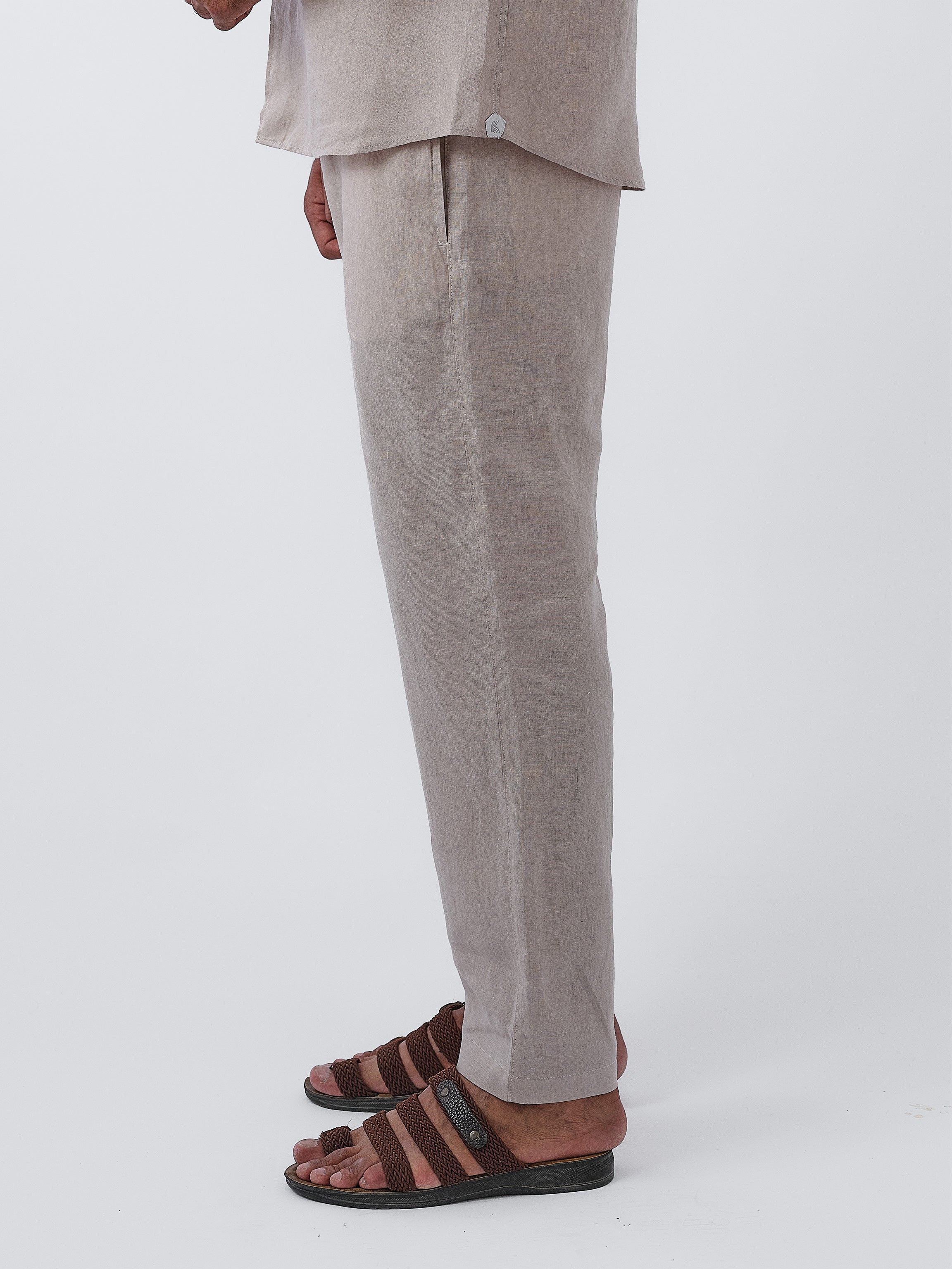 Person wearing beige pants and brown sandals on a white background