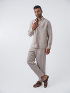 Man wearing a beige linen shirt and pants on a white background
