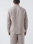 Man wearing a linen beige shirt and pants set on a white background
