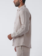 Man wearing a beige linen shirt and pants on a white background