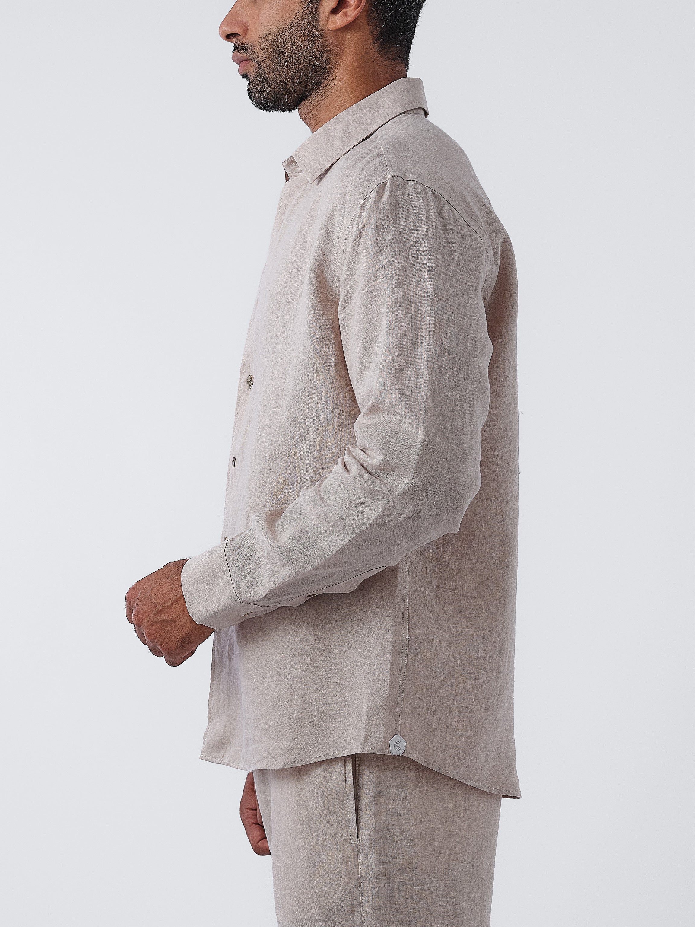 Man wearing a beige linen shirt and pants on a white background