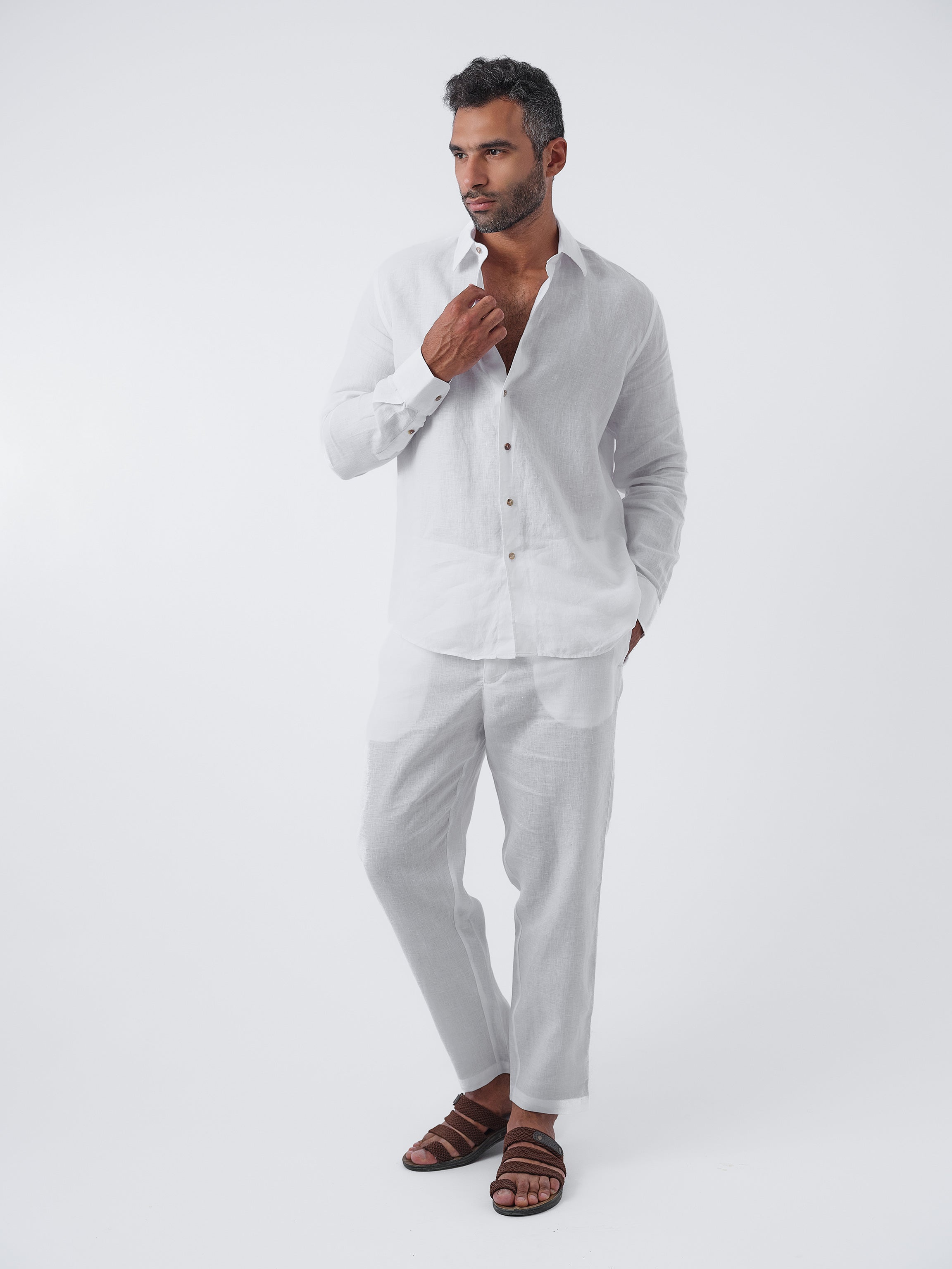 Man wearing a white linen shirt and pants on a white background