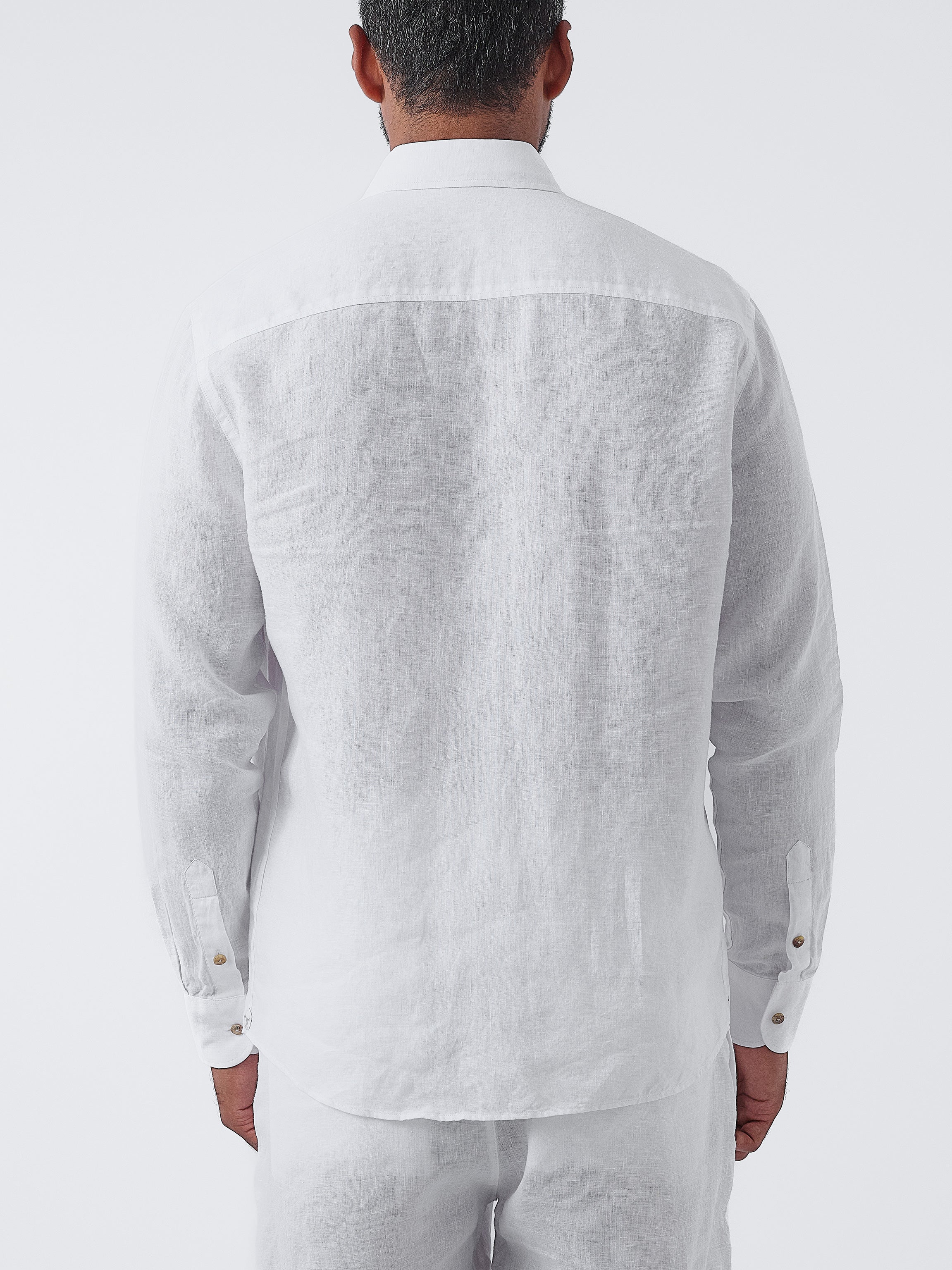 Man wearing a white linen shirt and pants on a white background