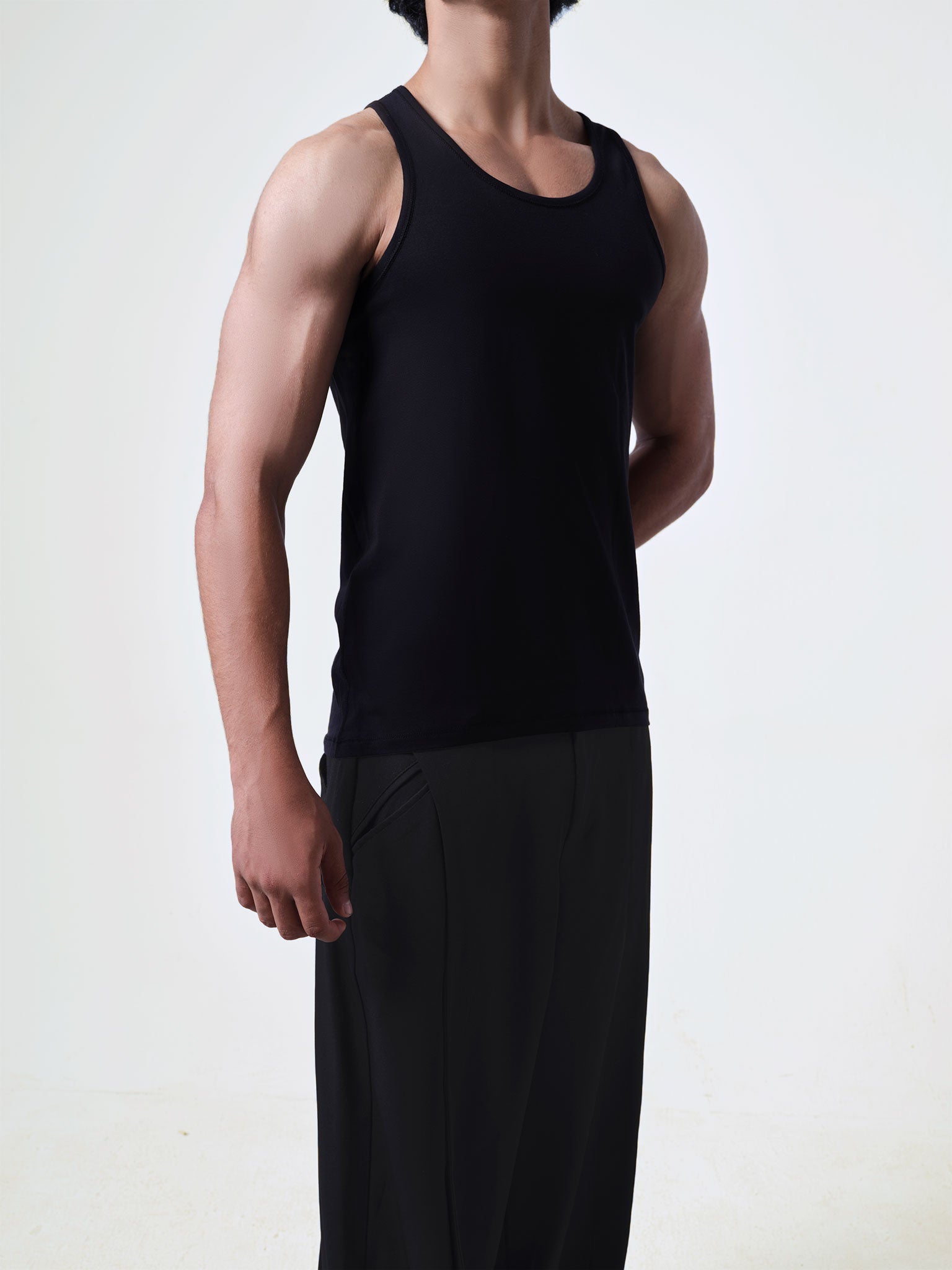 Person wearing a black tank top and pants on a white background