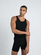 A male model wearing a black knit tank top with short sleeves.
