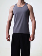 Person wearing a gray tank top and black pants on a light background