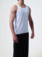 Person wearing a white tank top and black pants on a plain background