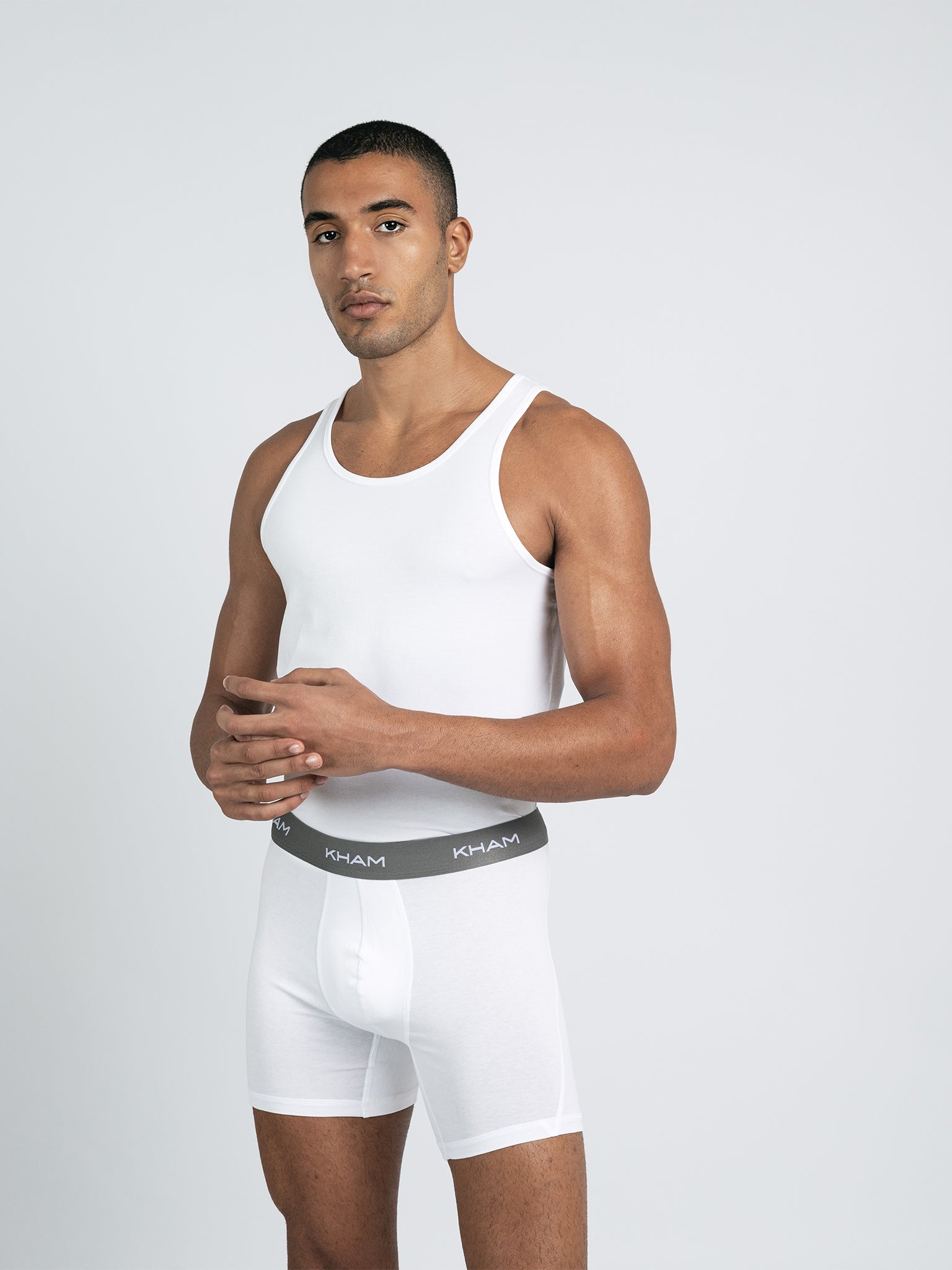 A male model wearing a white knit tank top with short sleeves.