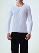 Person wearing a white long-sleeve crew neck shirt and black pants on a light gray background.